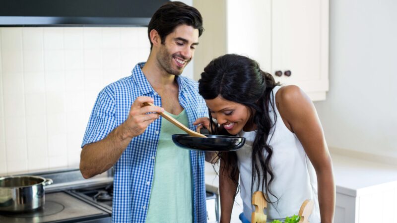 Young couple cooking food together in kitchen