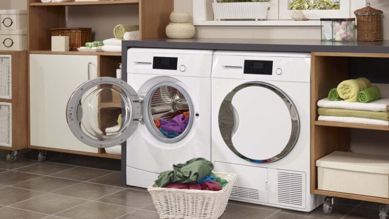 laundry room wiht washing machine and laundry in a basket in front