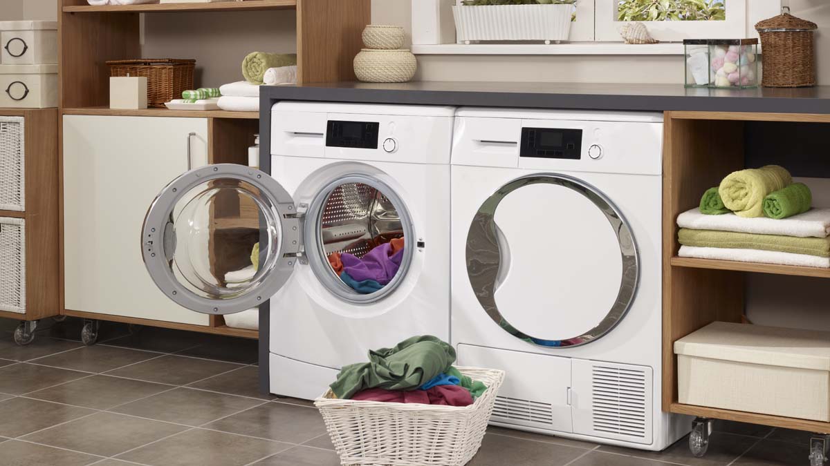 laundry room wiht washing machine and laundry in a basket in front